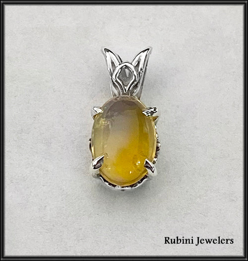 A gorgeous Ethiopian Opal with tones of yellow, green, and blue set in a sterling silver filigree pendant.